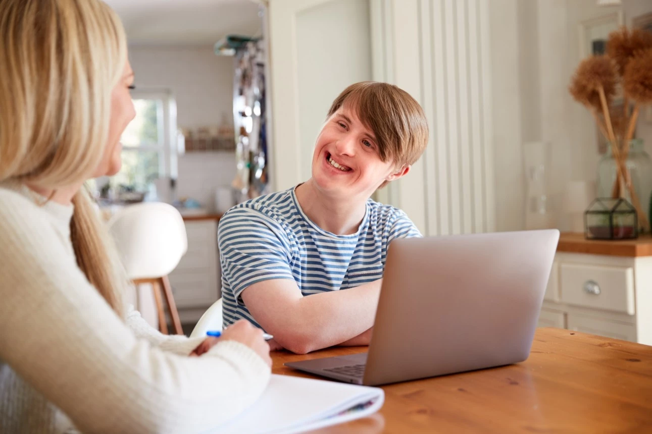 disabled young boy with down syndrome disability looking at caretaker